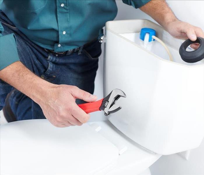 A person repairing a toilet.